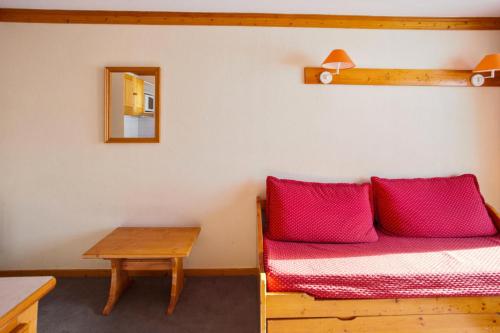 een kamer met een bed met rode kussens en een tafel bij Résidence Les Valmonts - maeva Home - 2 pièces 4 Personnes Sélection 71 in Saint-Martin-de-Belleville