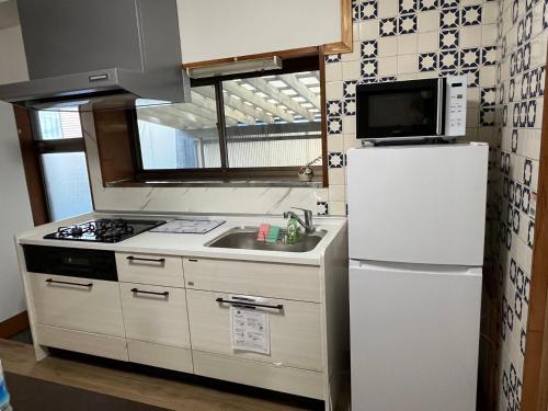 a kitchen with a white refrigerator and a sink at 富士山世界文化遺産三保松原久能山東照宮日本観光地第一日本平体験日本文化貸切民泊韶光 in Shizuoka
