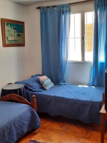 1 dormitorio con 2 camas y una ventana con cortinas azules en Departamento equipado Adolfo Calle en 