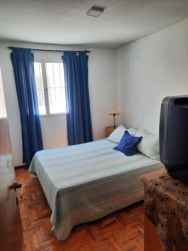 1 dormitorio con 1 cama grande y cortinas azules en Departamento equipado Adolfo Calle en 