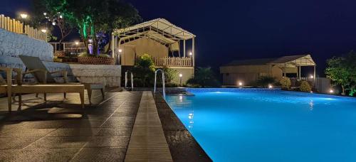 una piscina por la noche con luces azules en THE CANVAS LONAVLA, en Lonavala