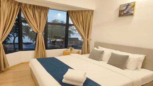 a bedroom with a large bed and a large window at Mutiara Melaka Beach Resort by Glex in Tangga Batu