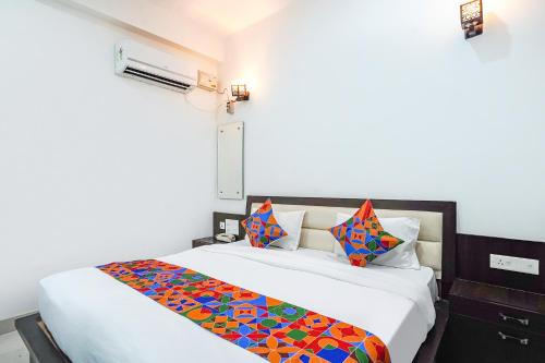 a bedroom with a large white bed with colorful pillows at FabHotel KP Palace in Agra