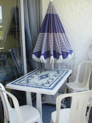 - une table et des chaises sur une terrasse couverte avec un parasol dans l'établissement Résidence Les Alpages - Studio au pied des pistes dans une résidence avec piscine extérieure MAE-9784, à Notre-Dame-de-Bellecombe