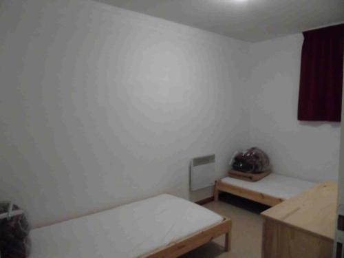 Cette chambre blanche comprend deux lits et une table. dans l'établissement Chalet Arrondaz - 2 Pièces pour 4 Personnes MAE-8614, à Modane