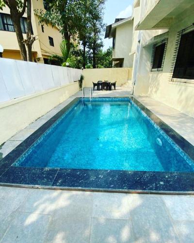a swimming pool with blue water in front of a building at THE PERFECT STAYS: SUPREME BLISS VILLA in Lonavala