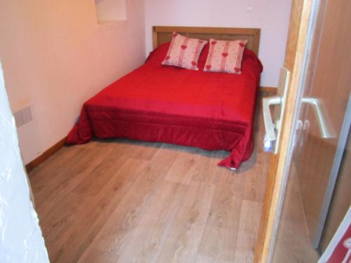 a small bedroom with a red bed and a wooden floor at Appartement 8 pers. avec vue montagne 70848 in Saint-Sorlin-dʼArves