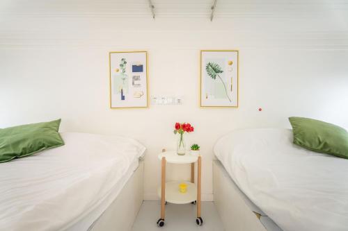 two beds in a room with a vase of flowers on a table at Hills &XING 1771 Homestay near Line1&2&13 and Shanghai People's Square in Shanghai