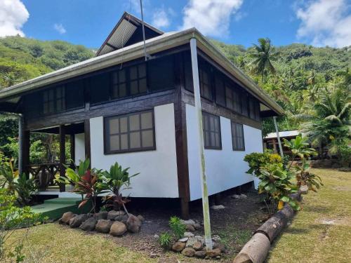 a white and black house with trees in the background at Pension Hibiscus Taha'a in Vaitoare