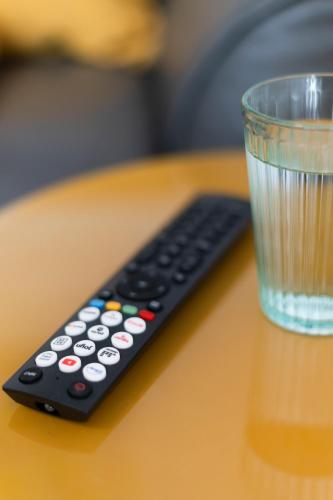 a remote control sitting on a table next to a glass at Akram Appartement III - Ruhig, Stadtnah in Hildesheim