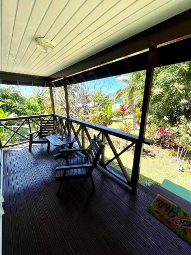 a porch with two chairs and a table on it at Pension Hibiscus Taha'a in Vaitoare