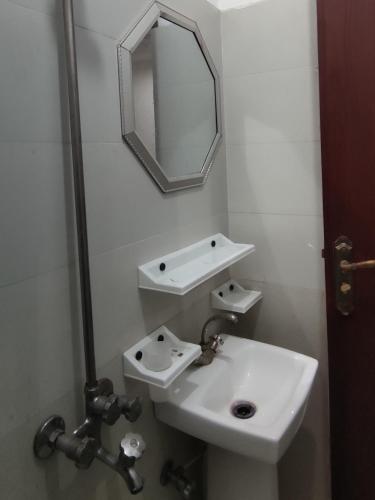 Baño blanco con lavabo y espejo en Comfy room, en Rawalpindi