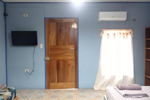 een kamer met een blauwe muur met een deur en een televisie bij Cabinas Centro Social Volio #6 in Talamanca