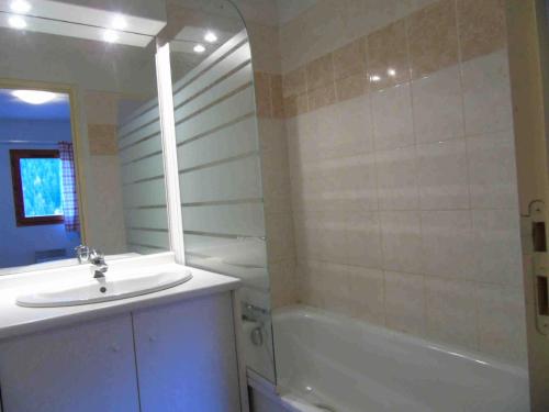 La salle de bains est pourvue d'un lavabo, d'une baignoire et d'un miroir. dans l'établissement Résidence Belvedere - 3 Pièces pour 8 Personnes 874, à Modane