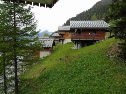 un groupe de bâtiments en bois sur une colline herbeuse dans l'établissement Résidence Cheval Blanc - 2 Pièces pour 6 Personnes MAE-8884, à Modane