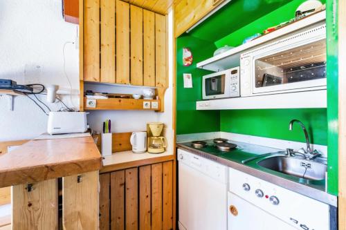 Elle comprend une petite cuisine avec des murs verts et un évier. dans l'établissement Résidences quartier Charmettoger - maeva Home - 2 Pièces 6 Personnes Budget MAE-3506, à Arc 1800