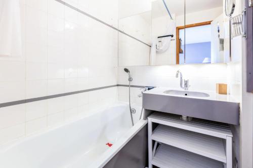 La salle de bains blanche est pourvue d'un lavabo et d'une baignoire. dans l'établissement Résidence L'Ours Blanc - maeva Home - 2 Pièces 4 Personnes Sélection MAE-3817, à Huez
