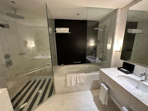 a bathroom with a shower and a sink and a tub at Emaar Fashion avenue-Formerly The Address Dubai Mall residence - Downtown by Suitestay Homes in Dubai