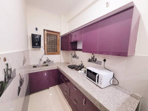 una cocina con armarios morados y microondas en una encimera en Utopiá 3BHK Entire Luxury Apartment In Noida 63, en Noida