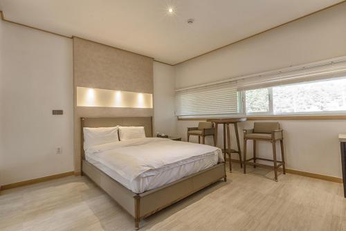 a bedroom with a bed and a table in it at Raffine Hotel in Gangneung