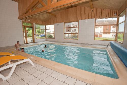 a large swimming pool with two people in it at Etoile des Neiges Piscine Spa Sauna in Métabief