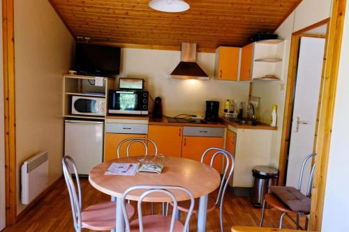 una pequeña cocina con mesa de madera y sillas en Gîte de France Chalet - Gîte de France 4 personnes 504, en Soursac