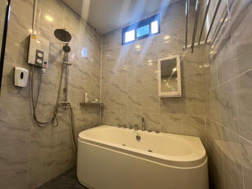 a bathroom with a bath tub and a shower at โค้งโดนัท พรีเมียม พูลวิลล่า in U Thong