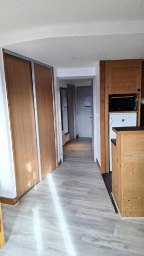 une cuisine vide avec des placards en bois et un couloir dans l'établissement Résidence L'Ours Blanc - maeva Home - 2 Pièces 5 Personnes Sélection MAE-3006, à Huez