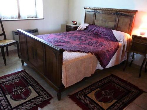 - une chambre avec un grand lit en bois et 2 tapis dans l'établissement Gîte de France à Saillac 2 épis - Gîte de France 2 personnes MAE-6334, à Saillac