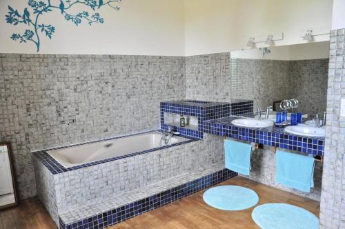 Un baño con azulejos azules, dos lavabos y una bañera. en Gîte de France Aux deux mésanges 4 épis - Gîte de France 10 personnes MAE-6364, en Sainte-Fortunade