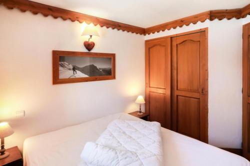 Schlafzimmer mit einem weißen Bett und einem Holzschrank in der Unterkunft Résidence La Ginabelle - maeva Home - 4 Pièces 6 Personnes Sélection 71 in Chamonix-Mont-Blanc