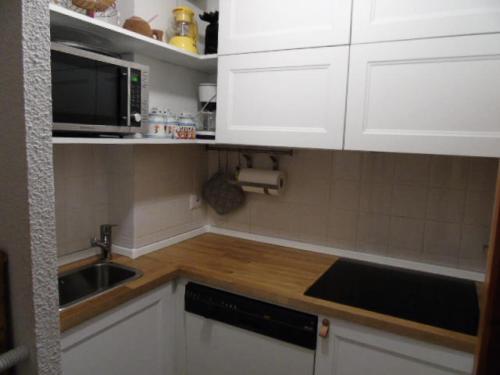 une cuisine avec des armoires blanches, un évier et un micro-ondes dans l'établissement Résidence Melezets - Studio pour 4 Personnes MAE-8974, à Modane