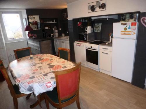 a kitchen with a table and a white refrigerator at Gîte de France La maisonnette 3 épis - Gîte de France 4 personnes MAE-6604 in Aubazines