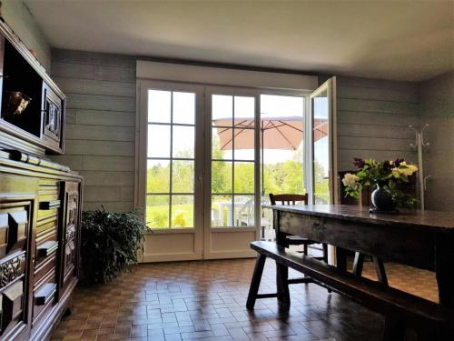 Cette chambre comprend une table et une porte coulissante en verre. dans l'établissement Gîte de France Au bord de l'eau 3 épis - Gîte de France 6 personnes MAE-6674, à Aubazines