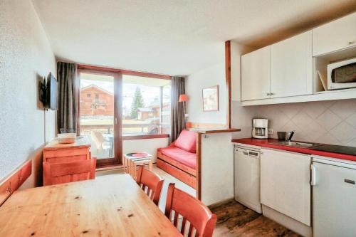une petite cuisine avec une table en bois et une fenêtre dans l'établissement Résidence Les Mélèzes - maeva Home - Appartement skis aux pieds vue montagne 2 pièces 4 personnes - Sélection MAE-9791, à Huez
