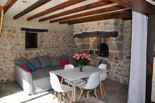 ein Wohnzimmer mit einem Sofa und einem Tisch mit Stühlen in der Unterkunft Gîte de France Le fournil 3 épis - Gîte de France 2 personnes 664 in Marcillac-la-Croisille