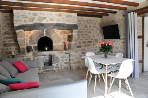 a living room with a table and a stone fireplace at Gîte de France Le fournil 3 épis - Gîte de France 2 personnes 664 in Marcillac-la-Croisille