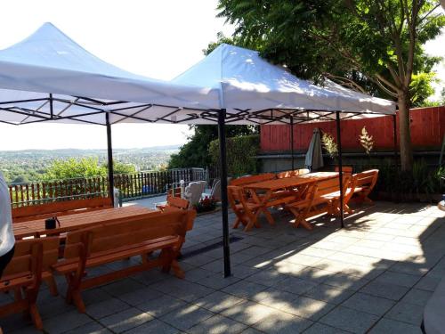 a white umbrella over tables and benches on a patio at Attila's Guest House in Budaörs