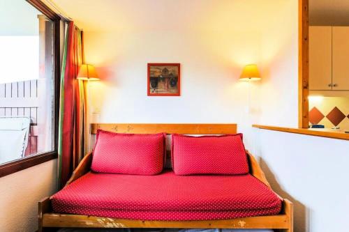 1 cama roja con 2 almohadas rojas en una habitación en Résidence Les Mélèzes - maeva Home - Studio 4/5 pers Sélection 44, en LʼHuez