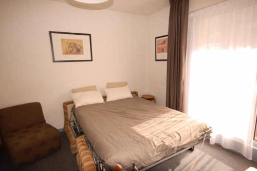 una camera con un letto e una sedia e una finestra di Résidence MARMOTTES - Studio pour 4 Personnes 924 a Gourette