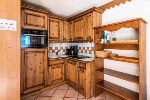 une cuisine avec des armoires en bois et un four à plaques de cuisson dans l'établissement Résidence La Ginabelle - maeva Home - 4 Pièces 6 Personnes - Prestige MAE-1506, à Chamonix-Mont-Blanc