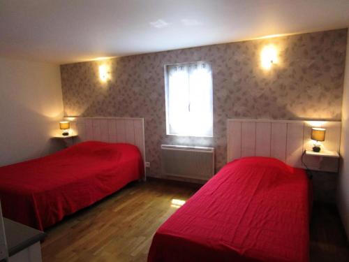 a bedroom with two red beds and a window at Gîte de France Gîte de la barbacane 3 épis - Gîte de France 5 personnes MAE-8884 in Curemonte