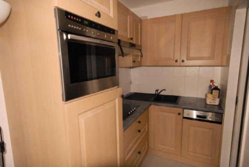 une cuisine avec des armoires en bois et un four à plaques de cuisson dans l'établissement Résidence MARMOTTES - Studio pour 6 Personnes MAE-8984, à Gourette