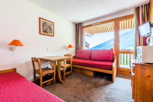 une chambre avec un canapé rouge, une table et une fenêtre dans l'établissement Quartier Crève Cœur - maeva Home - Studio 2 personnes Confort MAE-2092, à Valmorel