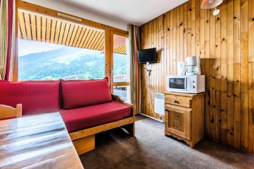 - un salon avec un canapé rouge et un four micro-ondes dans l'établissement Quartier Crève Cœur - maeva Home - Studio 2 personnes Confort MAE-2092, à Valmorel