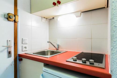 - une cuisine avec un évier et un comptoir rouge dans l'établissement Quartier Crève Cœur - maeva Home - Studio 2 personnes Confort 92, à Valmorel