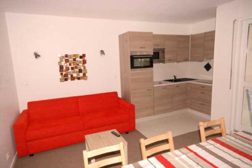 Il comprend un salon avec un canapé rouge et une cuisine. dans l'établissement Résidence ISARDS - 2 Pièces pour 8 Personnes 094, à Gourette
