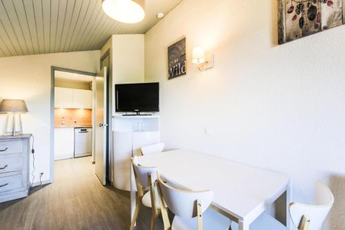 une salle à manger avec une table et des chaises blanches dans l'établissement Résidence Pierre de Soleil - maeva Home - Studio 4 personnes - Sélection MAE-1688, à Aime La Plagne