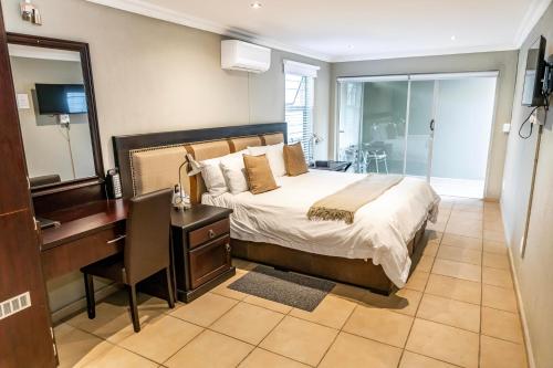 um quarto com uma cama, uma secretária e um espelho em Vanilla Guesthouse em Joanesburgo