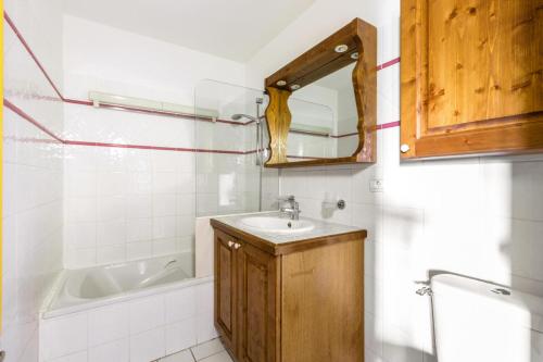 une salle de bain avec un lavabo, un miroir et une baignoire dans l'établissement Résidence Les Hauts Bois - maeva Home - Appartement 4 pièces 8 personnes Selection MAE-2806, à Aime La Plagne